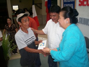 TAX MONEY GETTING TO THE PEOPLE. A city resident, one of the 200 city residents who qualify for the cash aid, receives the P500 one-time Katas ng VAT subsidy from DSWD secretary Esperanza Cabral as City councilor Danilo Batugan look on. (PIA)