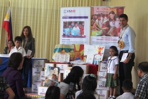 USAID Mission Director Gloria Steele and Senior Adviser for Administration John Spears pose with Cogon Elementary pupils Clyde Tumanda and Joanna Maarat, after the dignitaries received personalized "thanks you" cards from the kids. The kids handed the card during the turn-over of learning materials from the USAID's Basa Pilipinas program, for use of Cogon Grades 1-3 teachers. (rac/PIA-7/Bohol)  